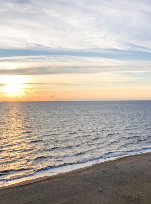 Light blue apartment buildings surround a grassy courtyard with trees under a partly cloudy sky.